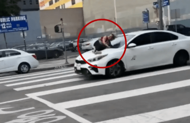 woman frantically holds onto hood
